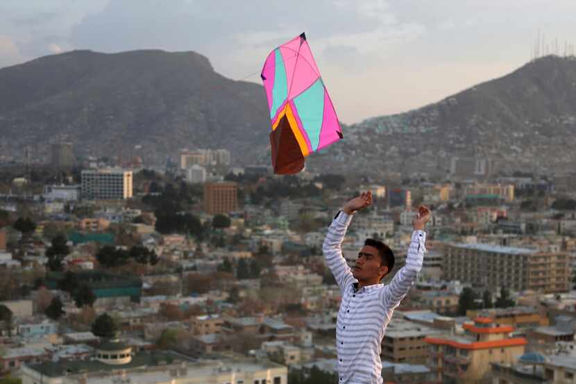 An Afghan launches a kite for his friend on hilltop during celebrations for Nowruz, the...