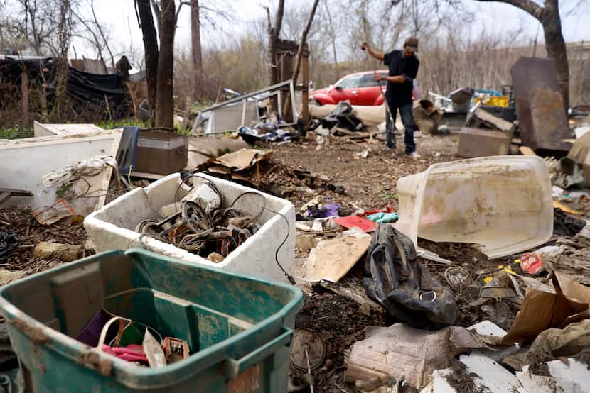 Urbano Zepeda helps clean an encampment Tuesday that sits on the edge of the Elm Fork of the...