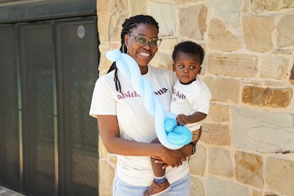 An African-American mother holds her infant son and smiles.