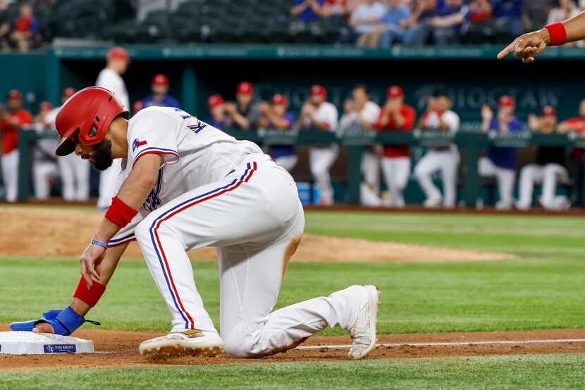 The Rangers' Isiah Kiner-Falefa arrives on third base at Globe Life Field after Brock Hold...