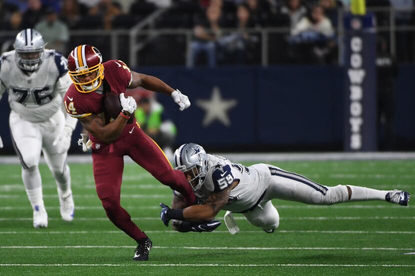 Redskins wide receiver Ryan Grant (14) is brought down by Cowboys linebacker Anthony...