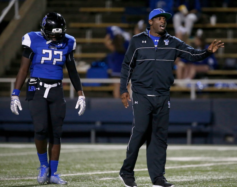 Trinity Christian-Cedar Hill offensive coordinator Deion Sanders (left) watches his players...