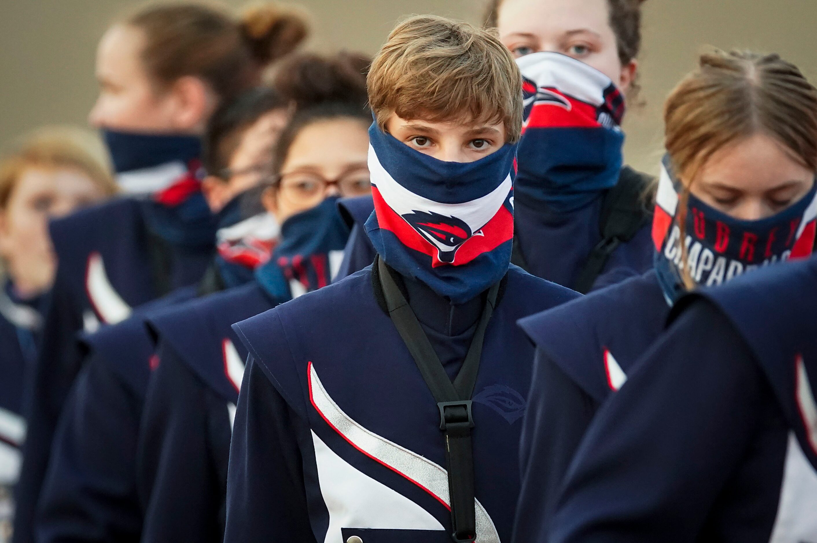 Aubrey band members wear face covering as the enter the stadium before a high school...