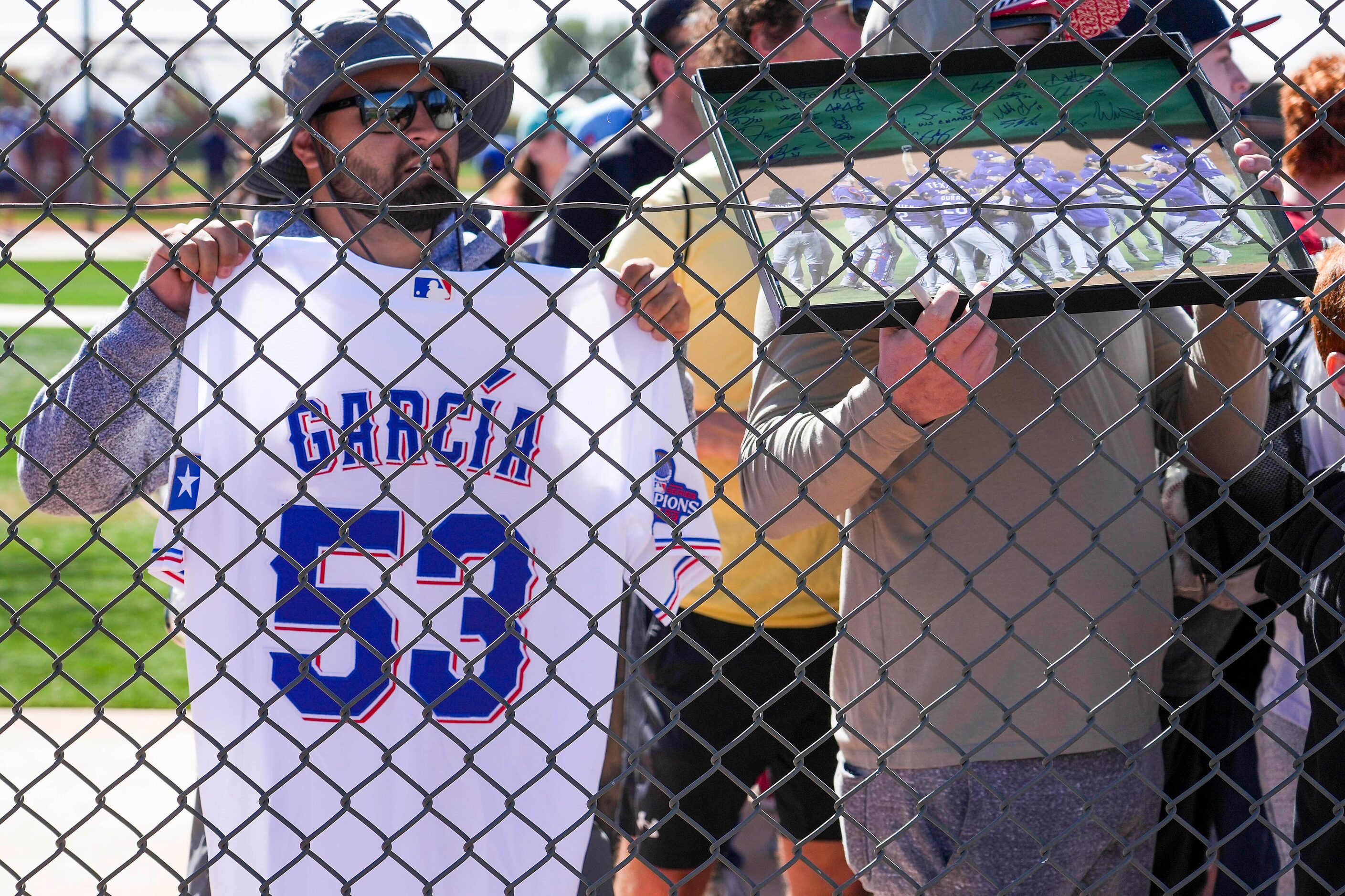 Fans hoping for autographs try to get the attention of Texas Rangers outfielder Adolis...