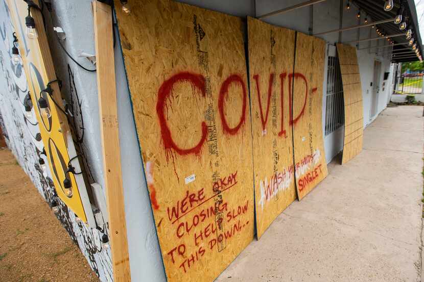Boarded up windows at Singleton Tattoo, which is closed because of the coronavirus outbreak,...