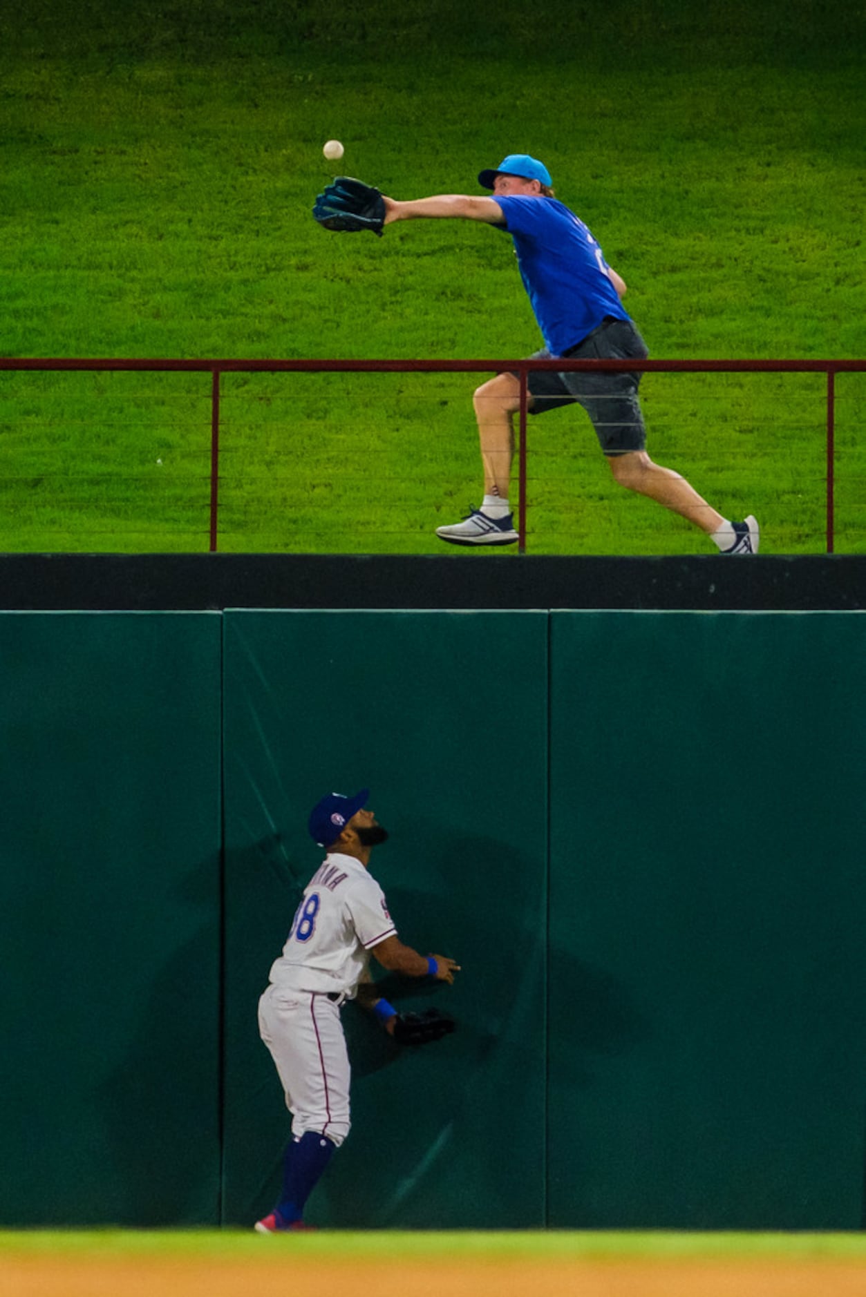 Texas Rangers center fielder Danny Santana watches as a fan makes the catch on a home run...