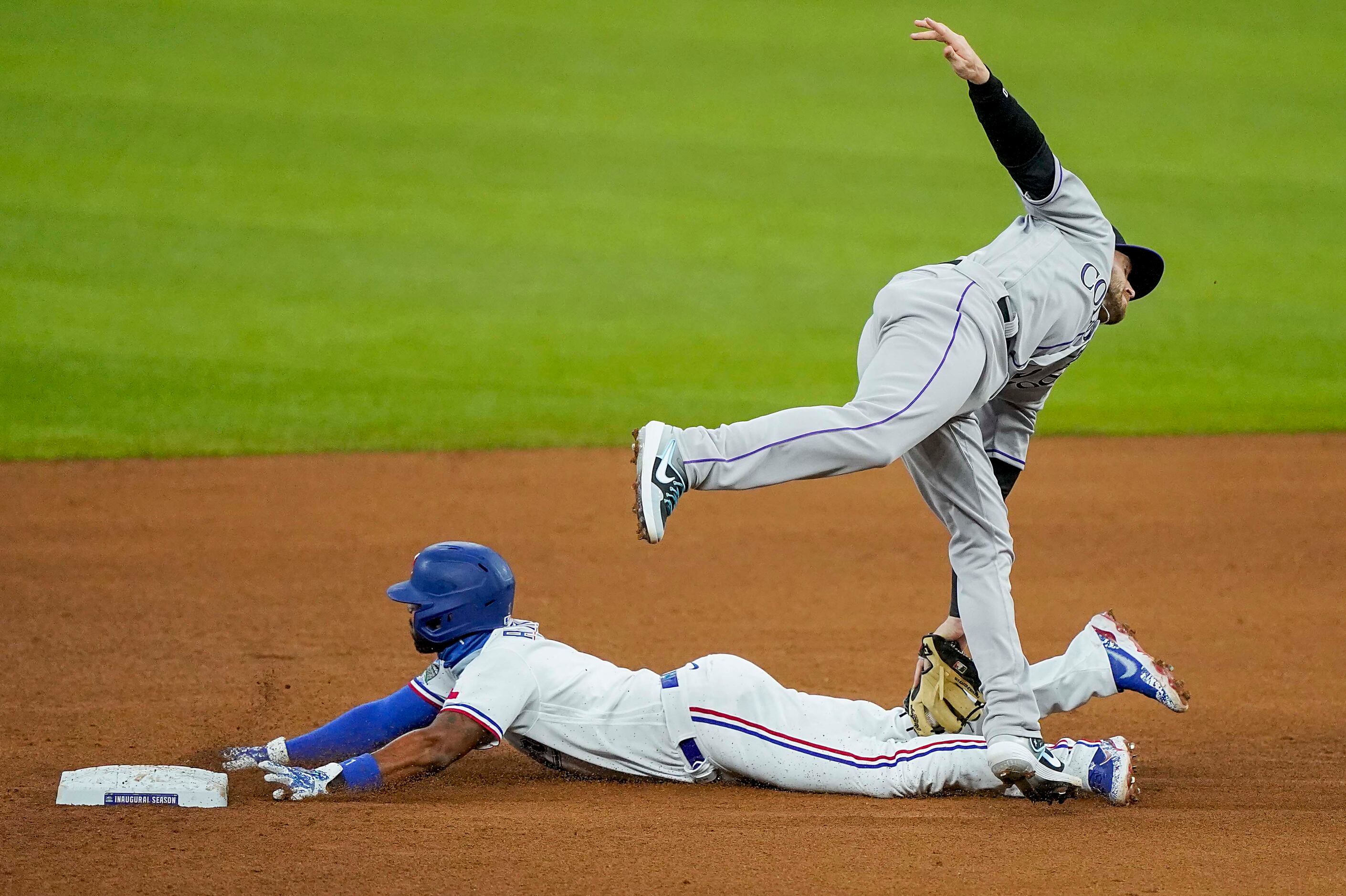 Colorado Rockies shortstop Trevor Story reaches down after fielding a high throw to tag out...