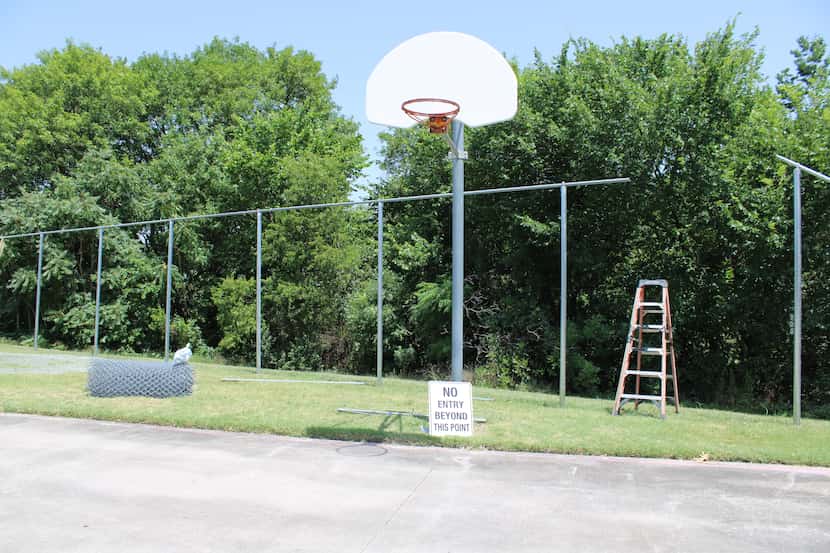 A company placed fencing behind a basketball court at Park Crest Elementary School on July...