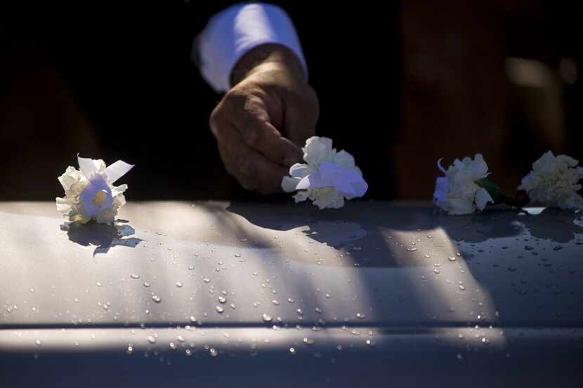 On Nov. 7, 2009, a flower is placed on a casket by a pallbearer during a funeral in St....