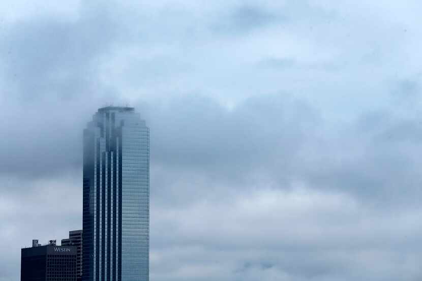 Lingering clouds drifted through the Bank of America building in downtown Dallas as a cold...