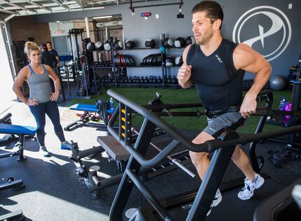 Paradigm Gym owner Brian Casad works out on a Matrix machine while his sister, co-owner and...