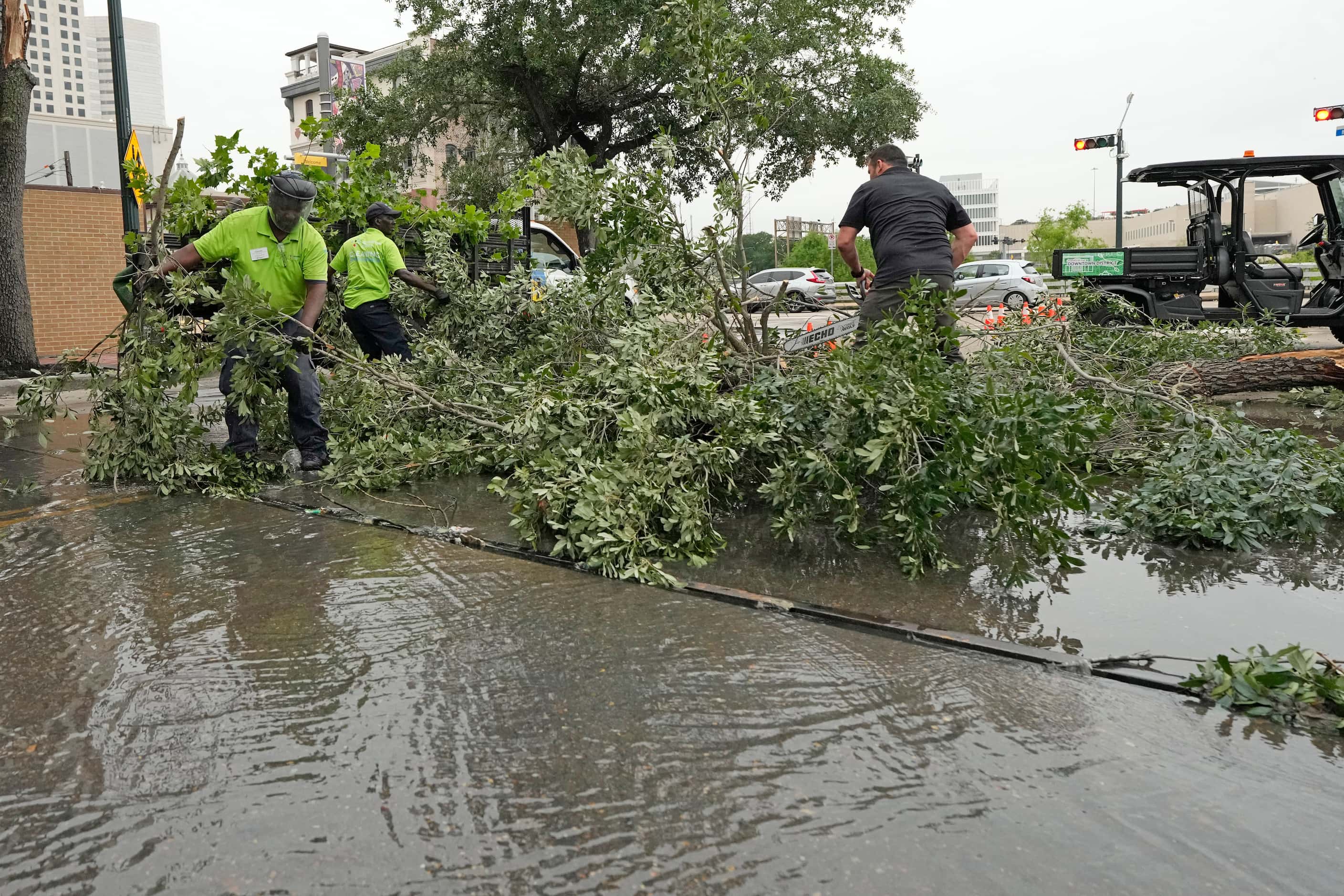 Workers remove fallen tree limbs from a downtown street in the aftermath of a severe...