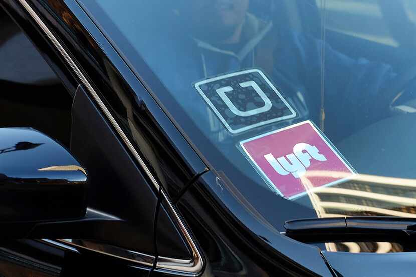 FILE - In this Tuesday, Jan. 12, 2016, file photo, a driver displaying Lyft and Uber...