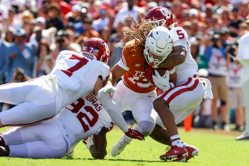 Texas wide receiver Jordan Whittington (center) gets locked by Oklahoma linebacker Jaren...