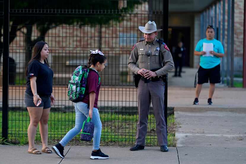 Students arrive at Uvalde Elementary, now protected by a fence and Texas State Troopers, for...