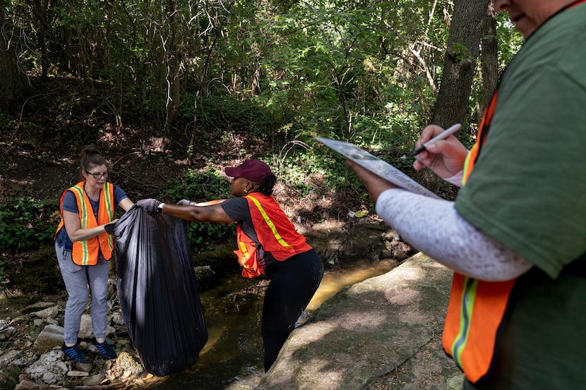 Volunteers Cynthia Smoot and Angelita Howard collect trash as Thelva Balkus counts the items...