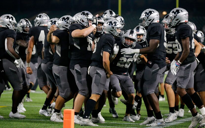 Arlington Martin quarterback Zach Mundell (center) is congratulated by teammates after...