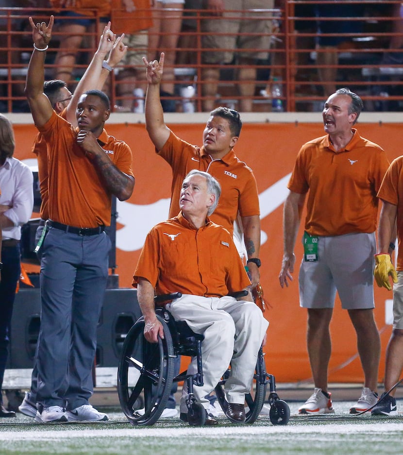 Texas Governor Greg Abbott, seated center, watches the third quarter of a college football...