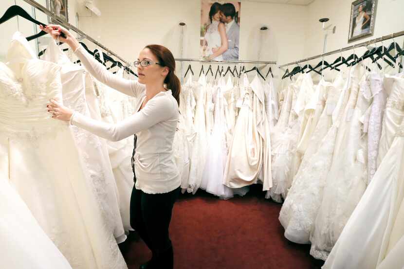 Coming Attractions Bridal & Formal Shop bridal consultant Danielle Snyder hangs a dress at...