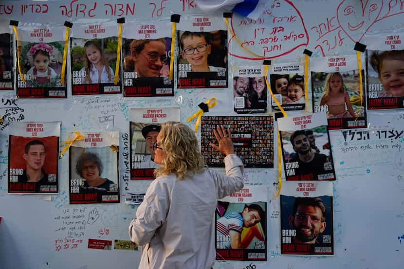 A woman looks at photographs of hostages, mostly Israeli civilians who were abducted during...