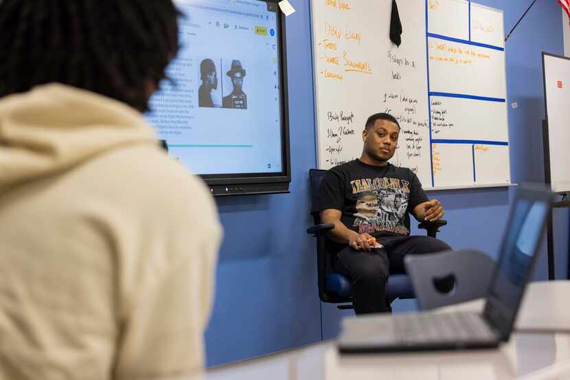 Teacher Joshua Castille (center) listens to senior Kenneth Haggerty, 18, as he discusses...