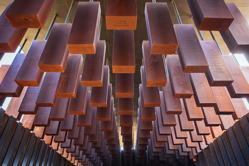 Eight hundred weathered steel columns, each one etched with the names of lynching victims,...