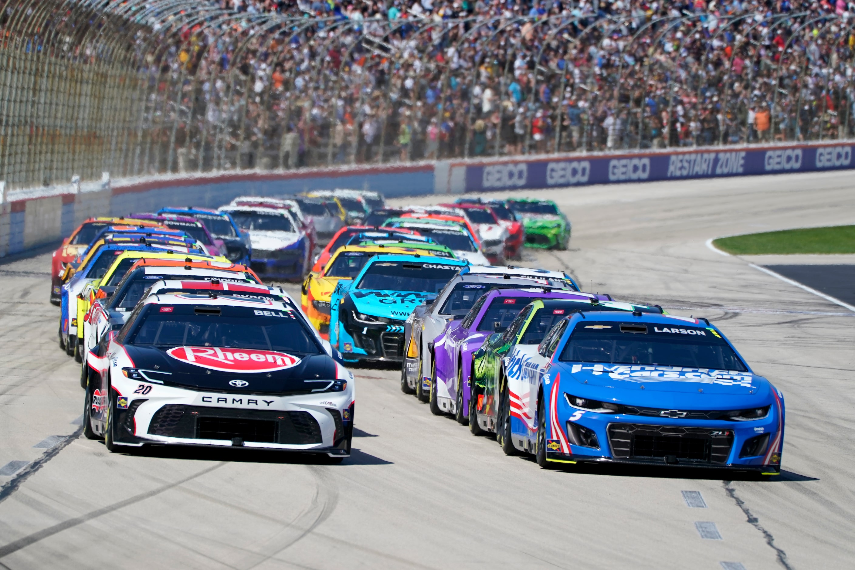 Christopher Bell (20) and Kyle Larson (5) lead the field into Turn 1 on a restart during the...