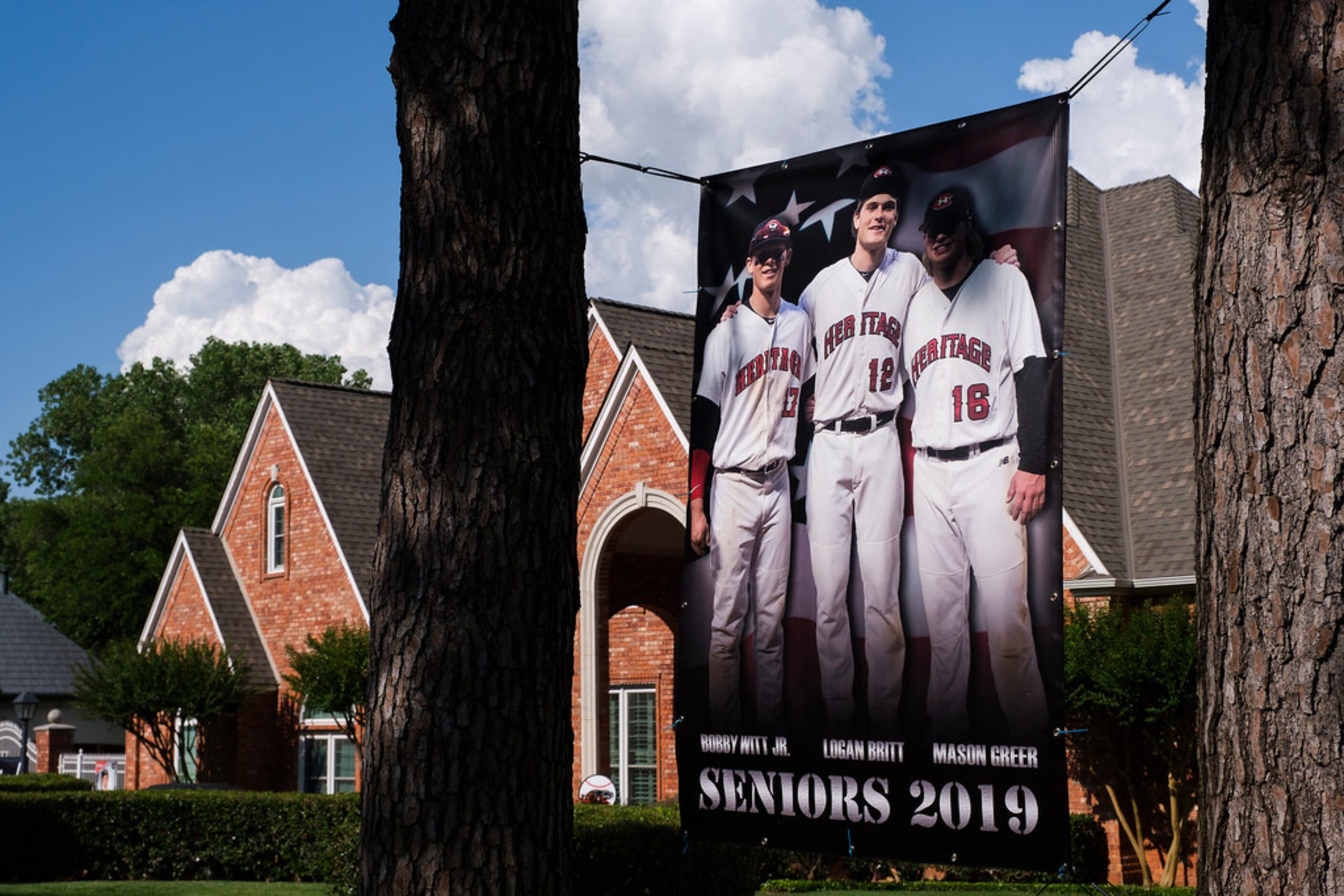 A banner showing Bobby Witt Jr. with teammates Logan Britt and Mason Greer hangs outside...