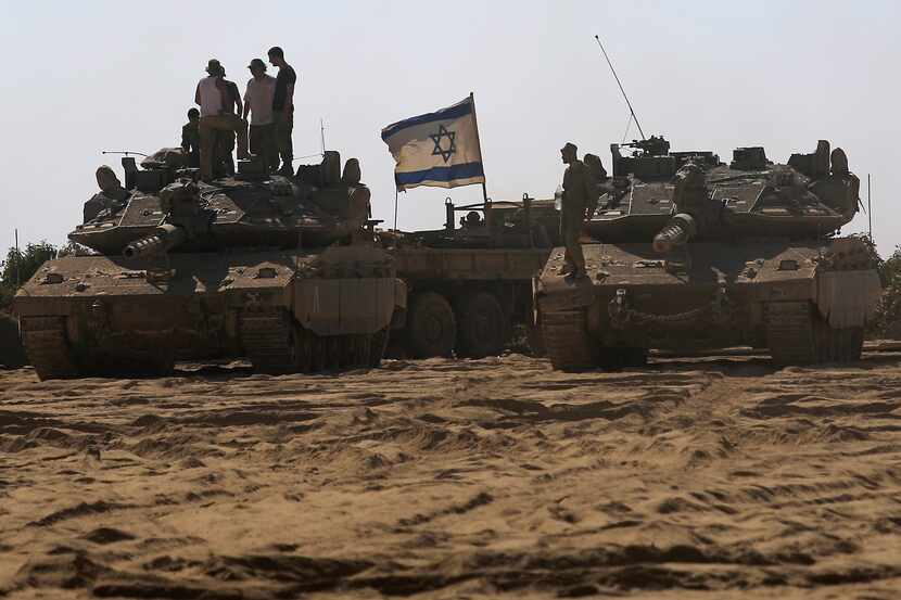 Israelis soldiers stand on top of tanks in a staging area near the Israel Gaza border,...