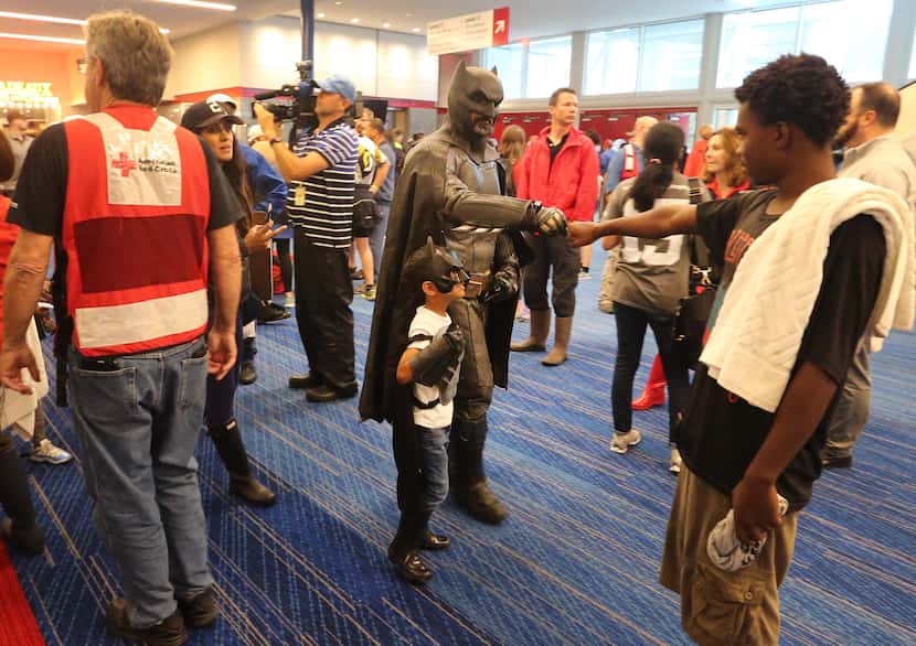 A man dressed as Batman shakes hands with people as they arrive at the Red Cross shelter at...