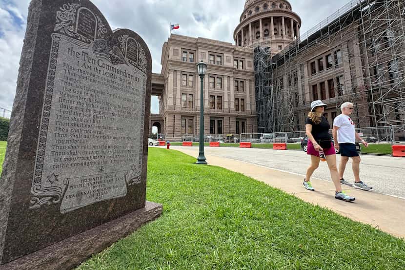 Visitors walk past a monument of the Ten Commandments outside the Texas Capitol on June 20,...