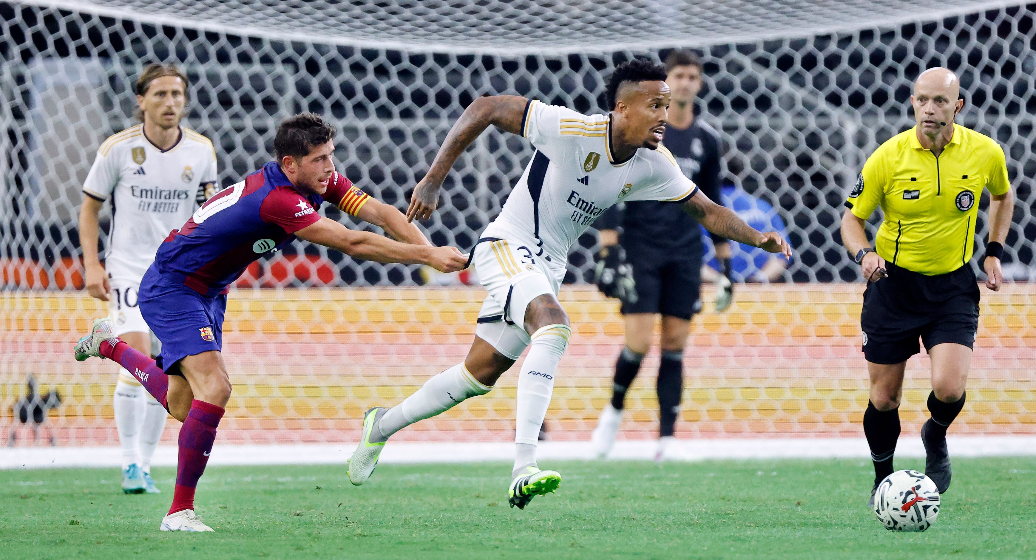 Barcelona defender Sergi Roberto (20) hangs onto the jersey of Real Madrid defender Éder...