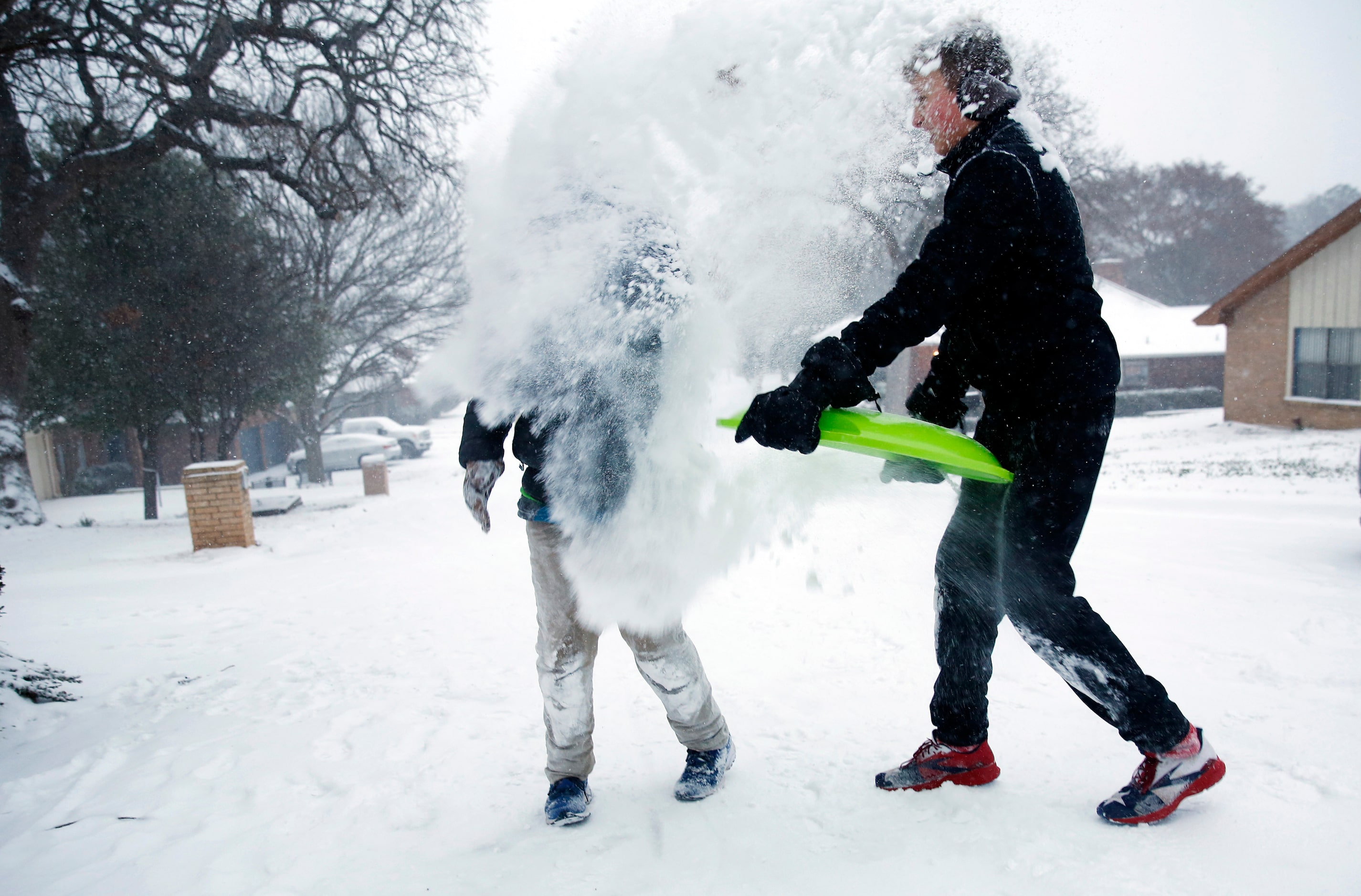 Owen Hulme (right) douses his brother Mitchell Hulme with a sled full of snow while sledding...