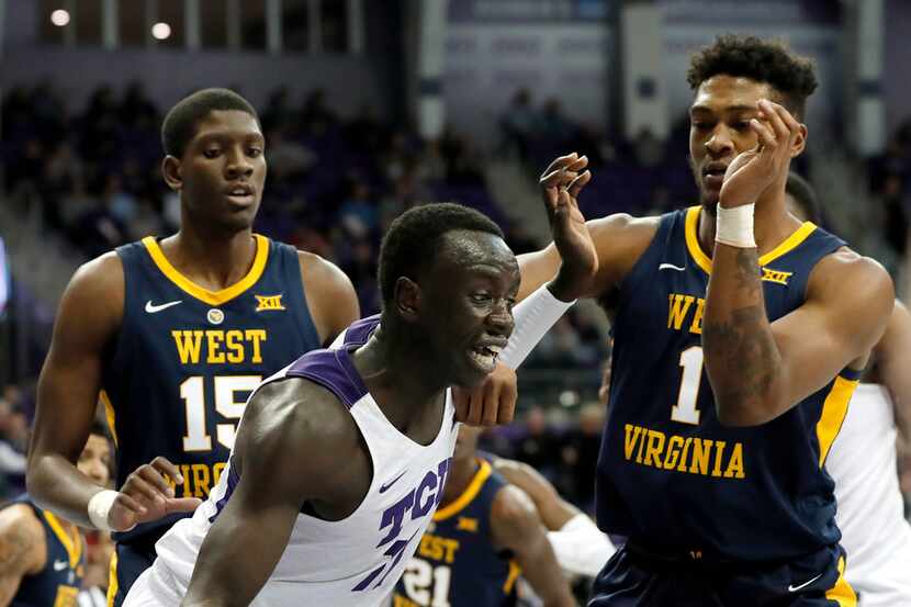 TCU forward Lat Mayen (11) works against West Virginia forward Lamont West (15) and forward...