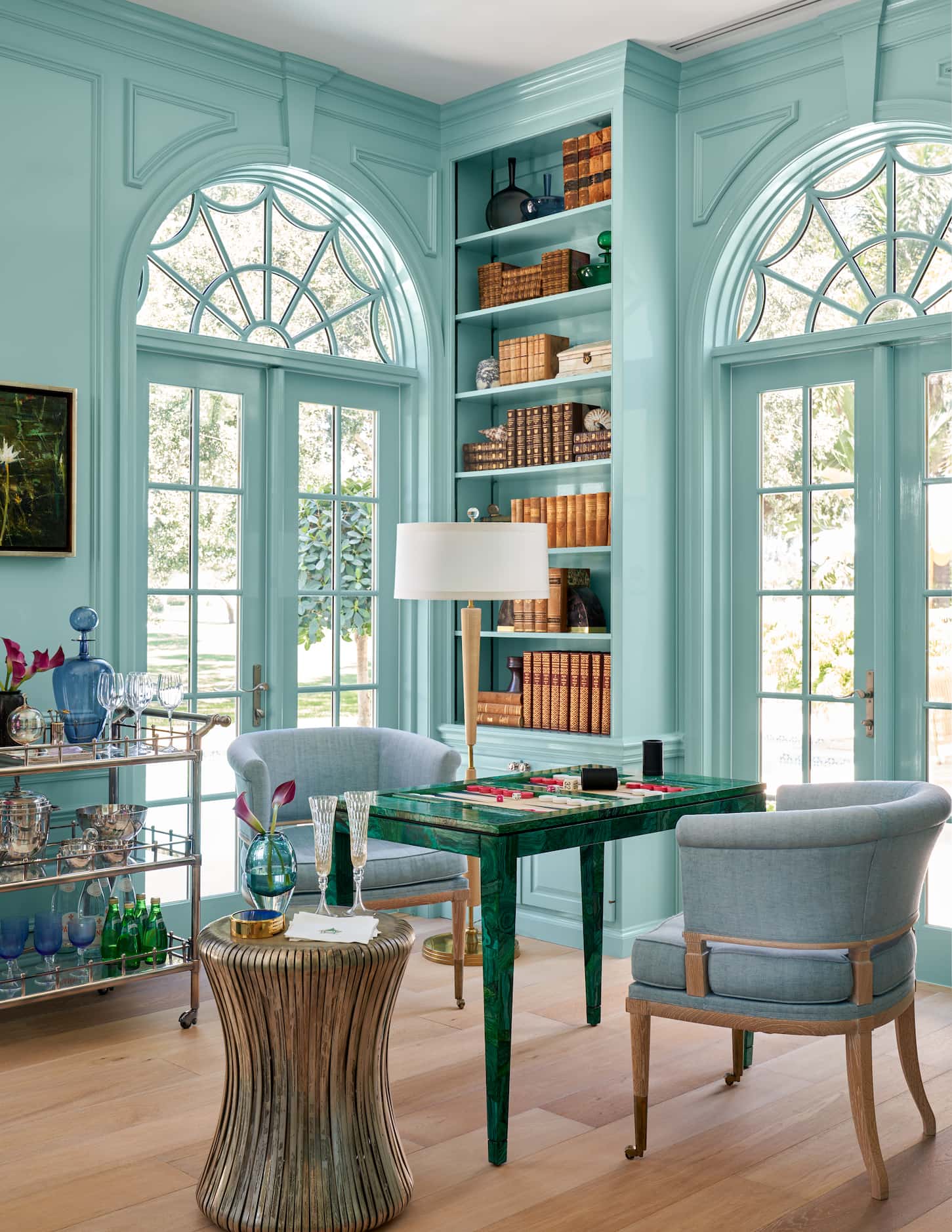 Bright blue library with green game table, bar cart, two club chairs