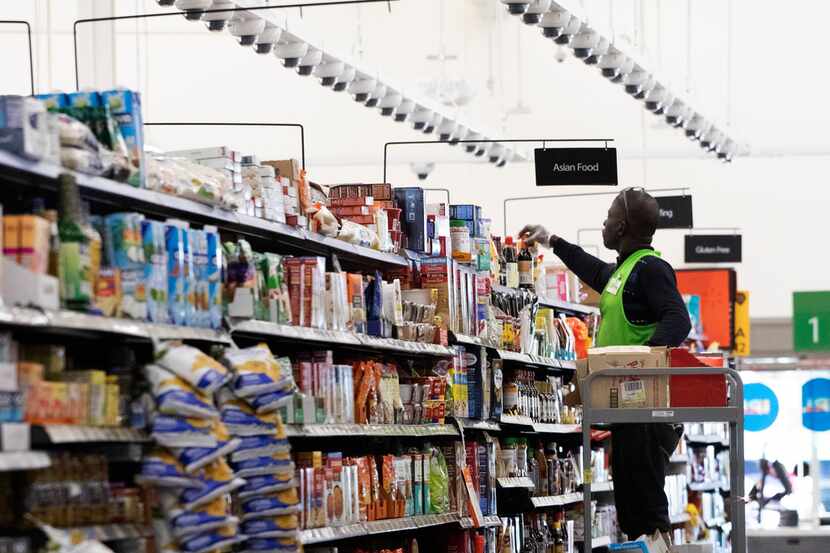 A Walmart associate arranges items on a shelf at a Walmart Neighborhood Market on April 24...