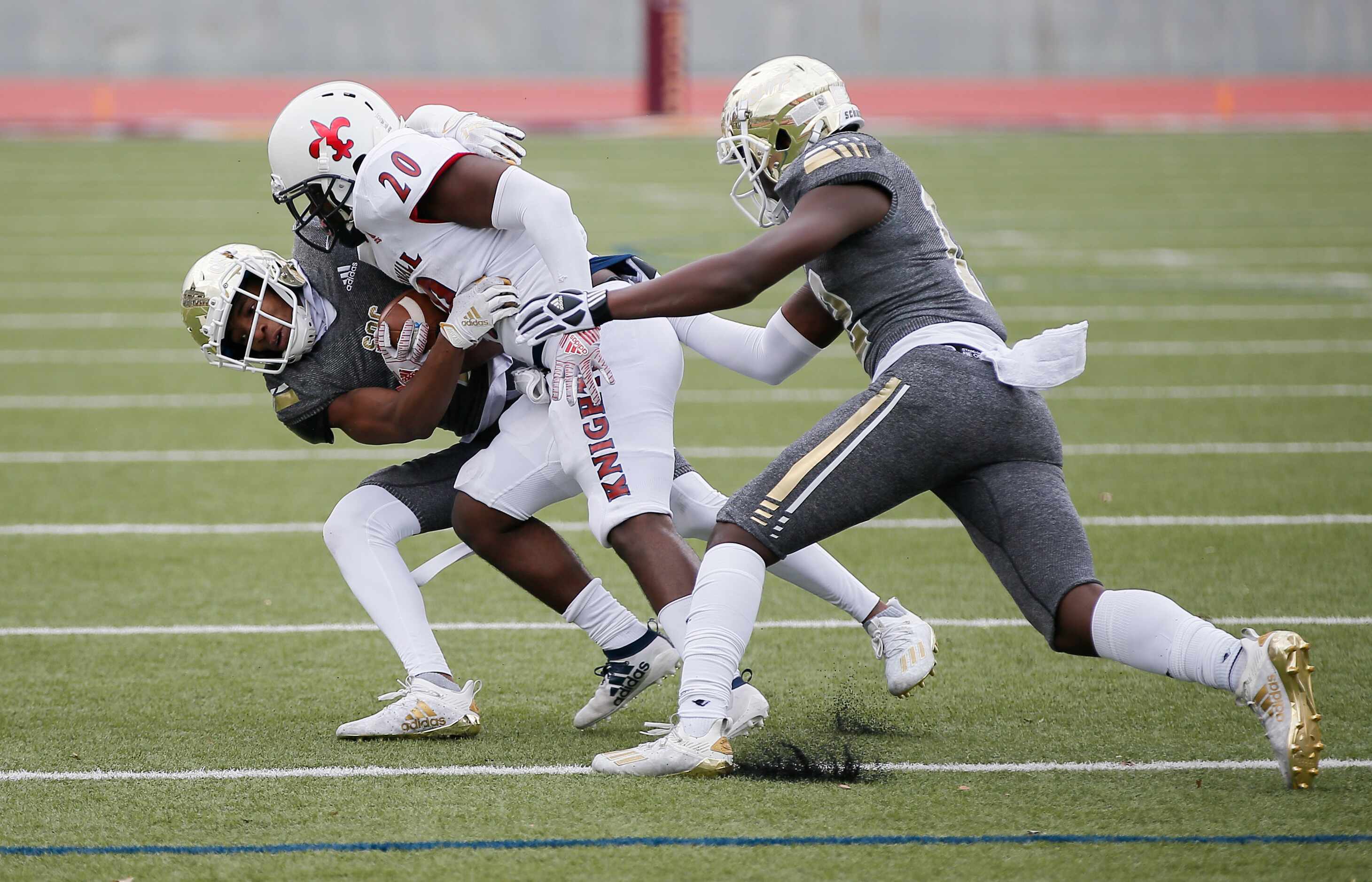 Kimball senior running back Jermius Johnson (20) is tackled by South Oak Cliff sophomore...