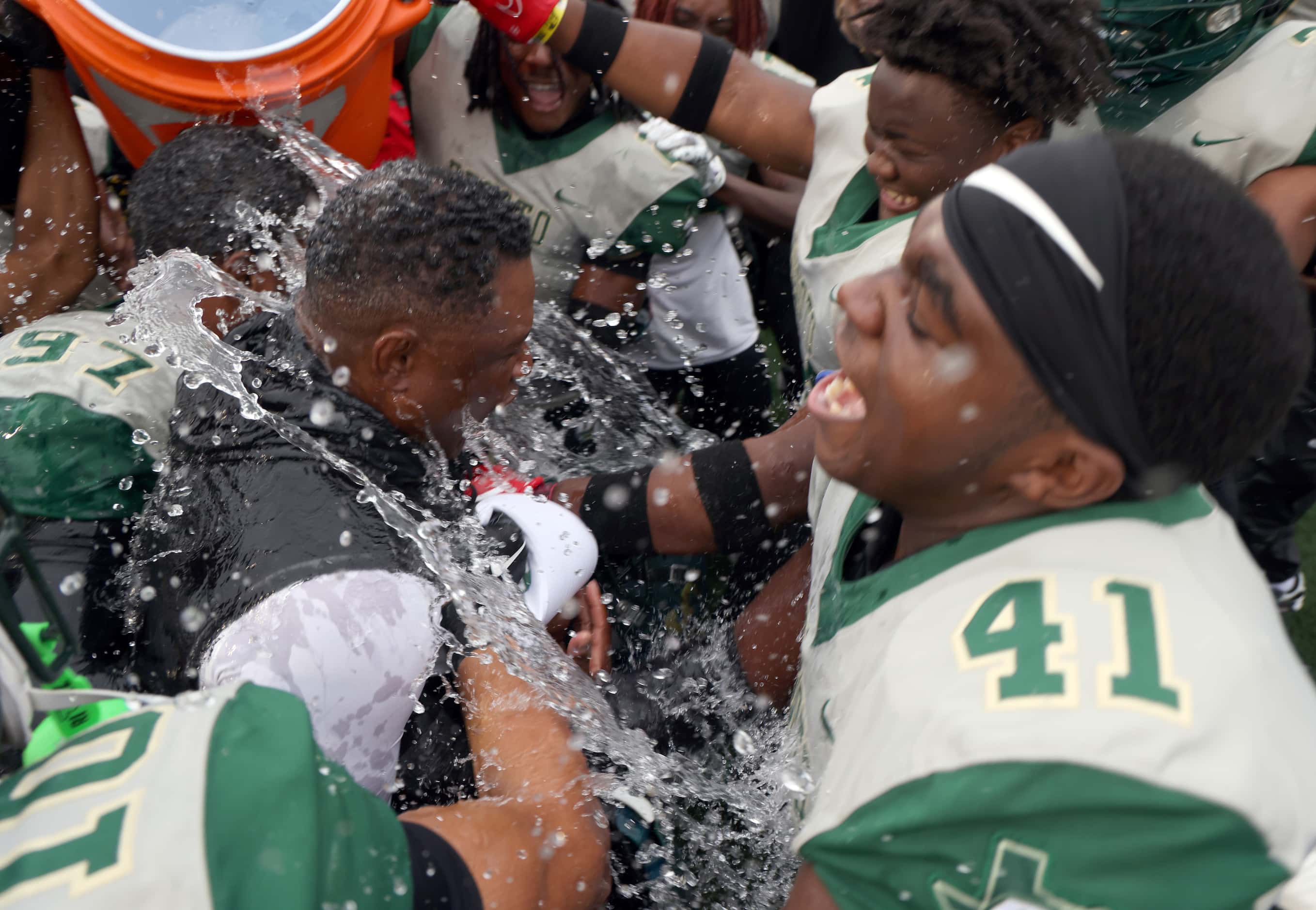 DeSoto head coach Claude Mathis, center left, is doused with ice and water at midfield by...