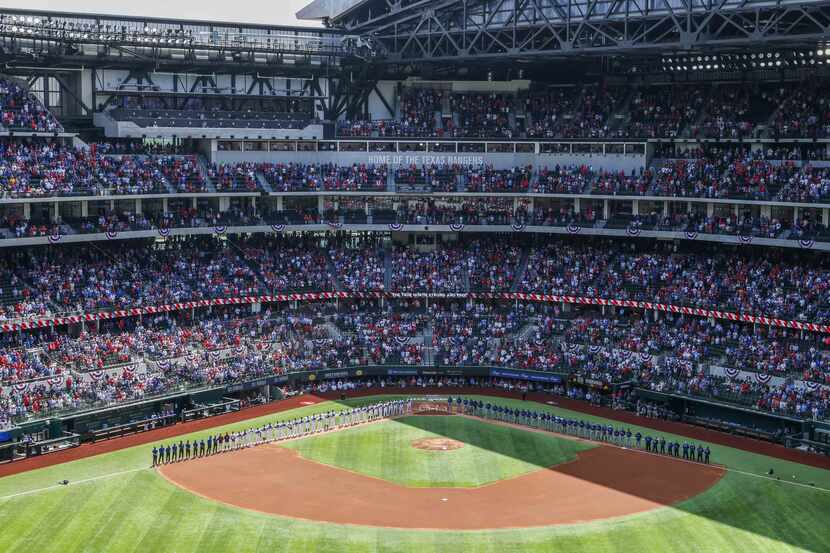 Texas Rangers and Toronto Blue Jays teams line up during the national anthem at the Globe...