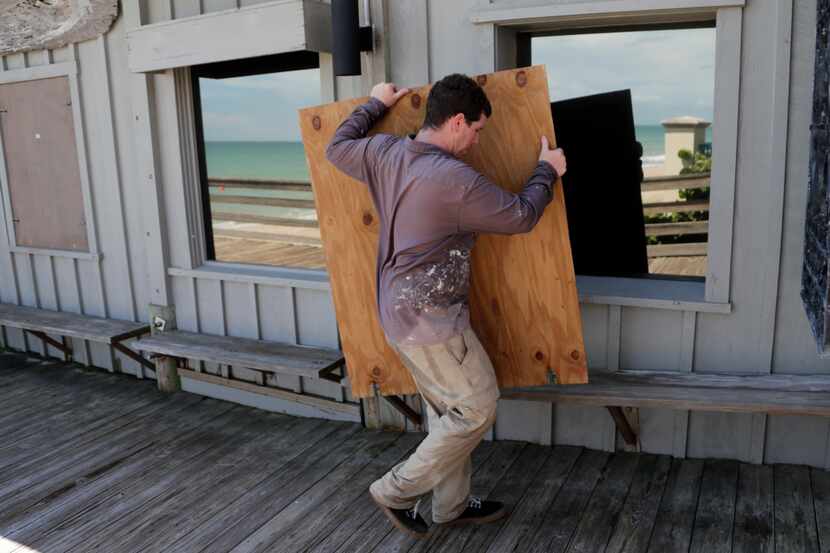 Lyle Fidgeon coloca páneles de madera para cubrir las ventanas en un restaurant en Vero...