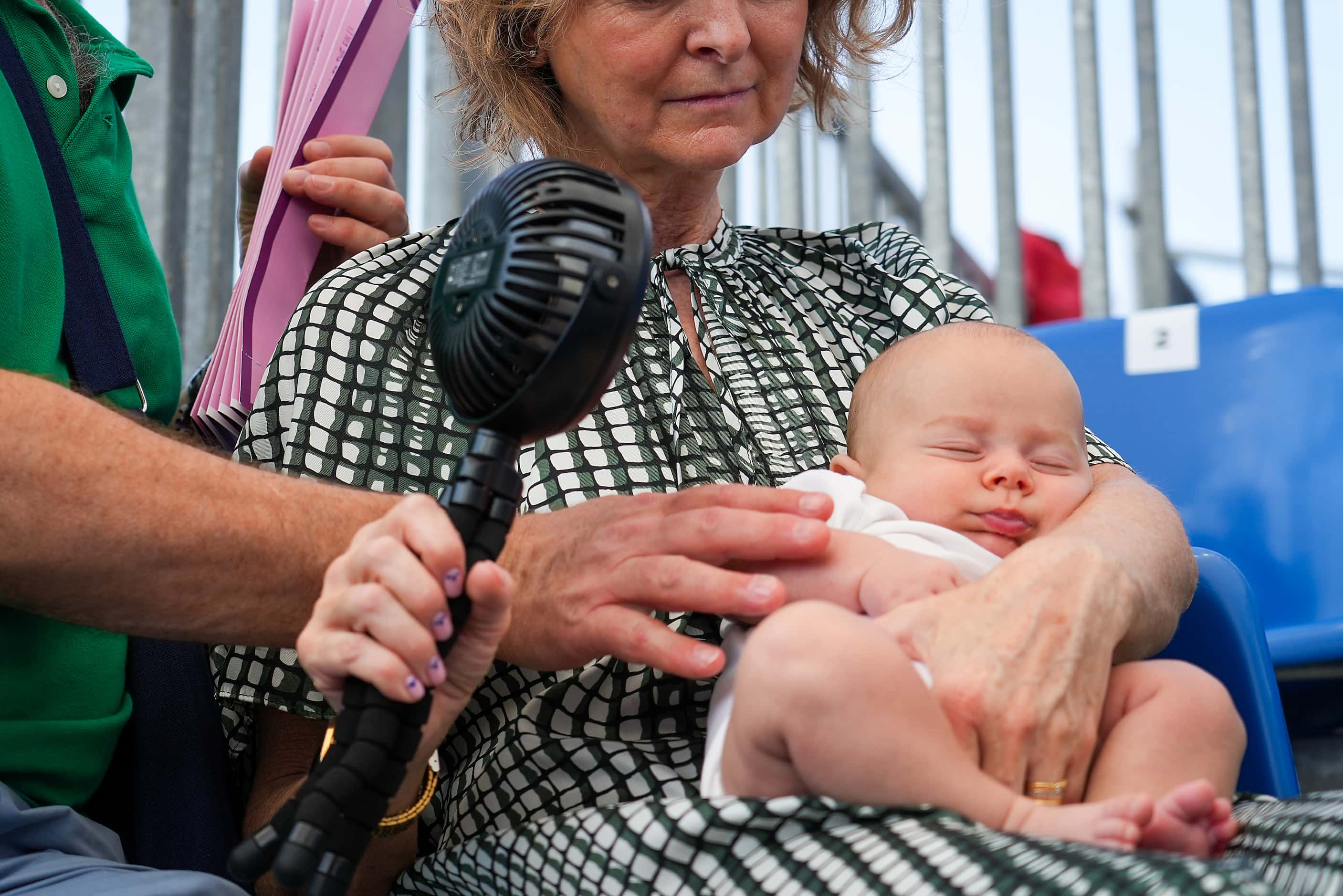 Spectators cool off a baby with a portable fan while watching 3x3 basketball at the 2024...