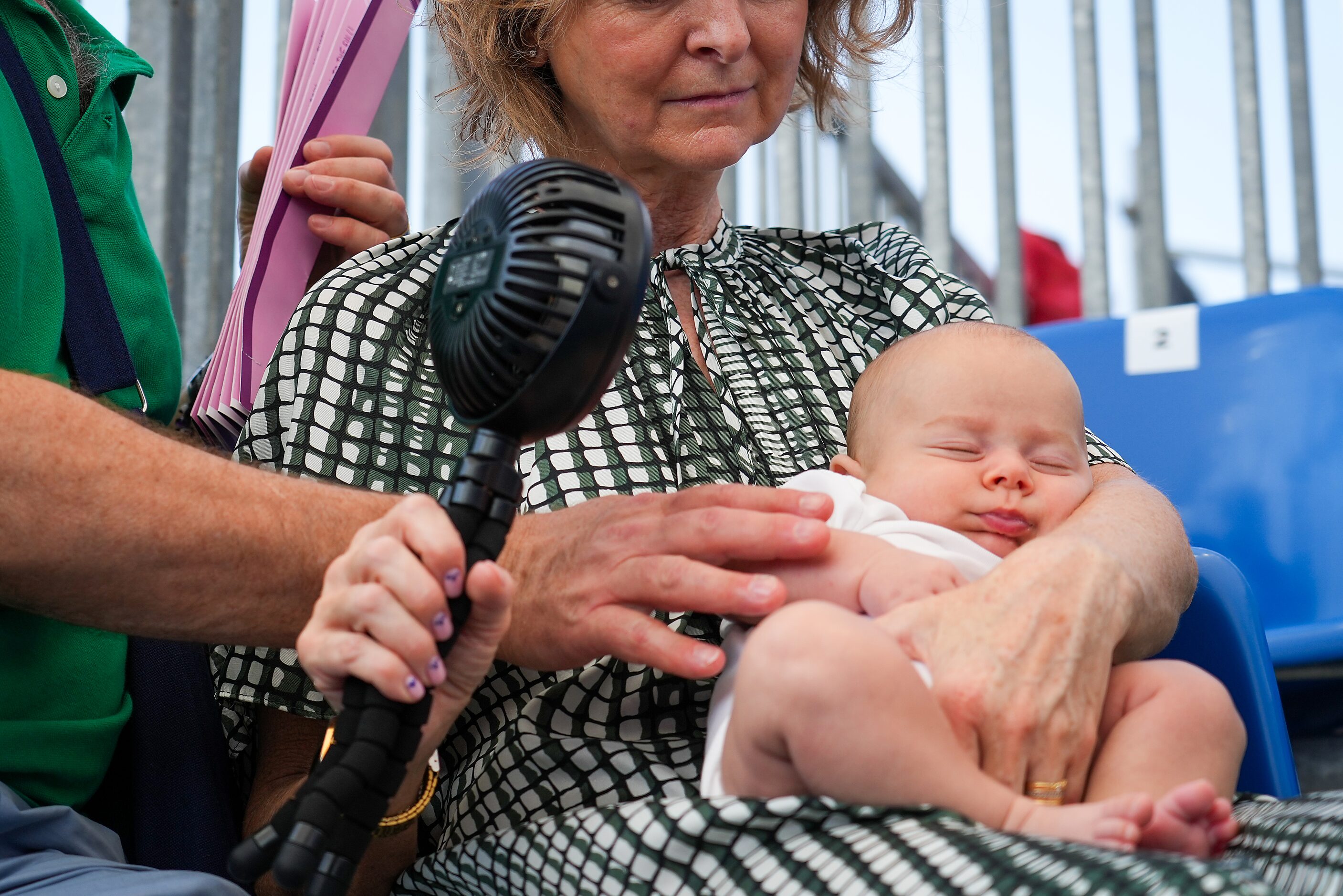 Spectators cool off a baby with a portable fan while watching 3x3 basketball at the 2024...