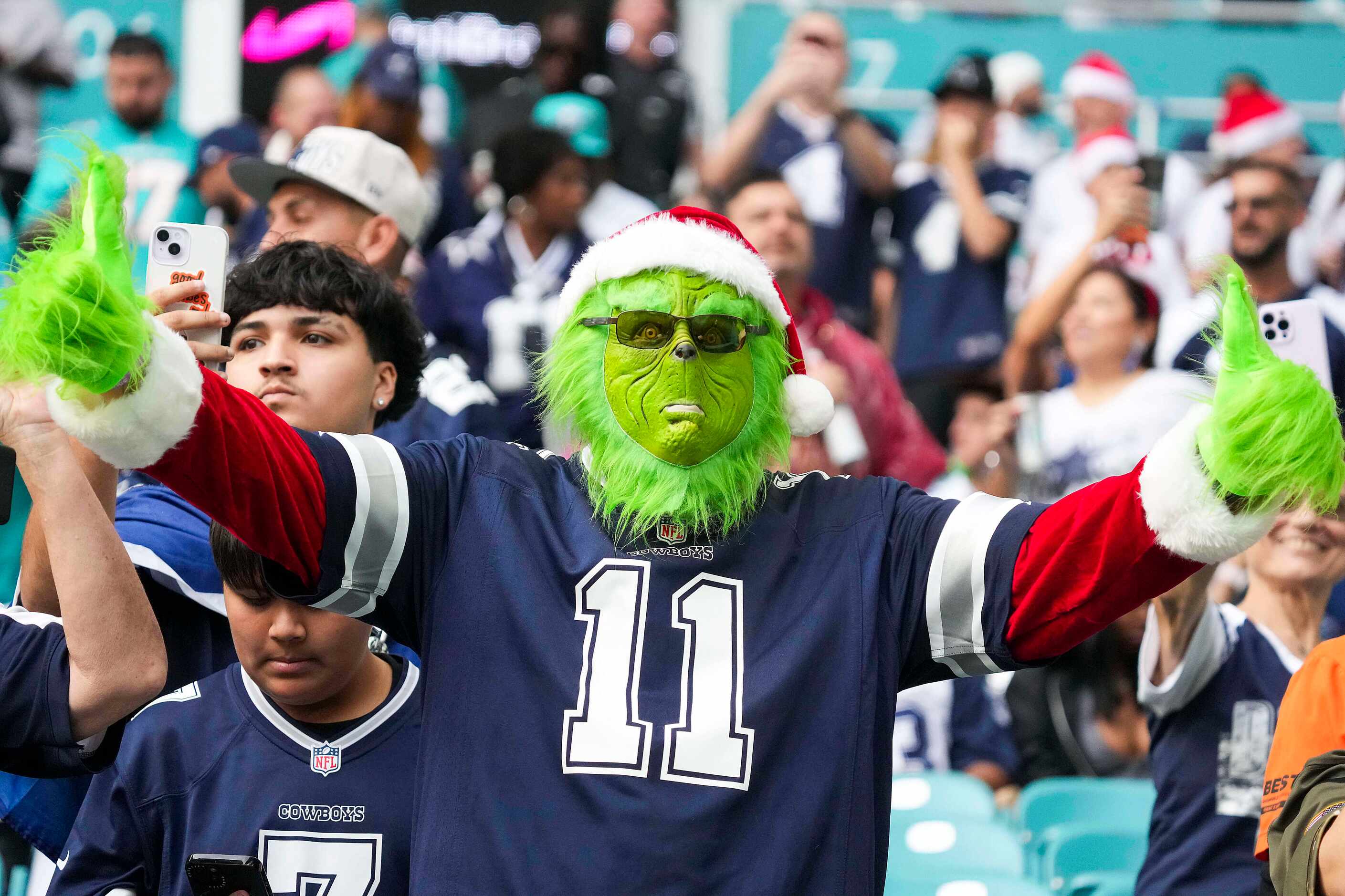 A Dallas Cowboys fans dresses as the Grinch cheers as the team warms up before an NFL...