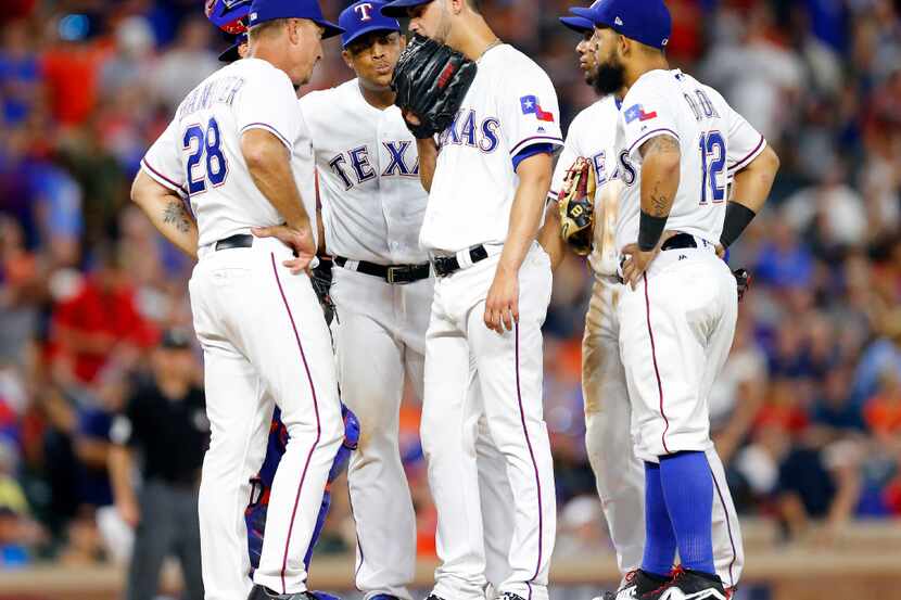 Texas Rangers relief pitcher Alex Claudio (center) receives a visit to the mound before...