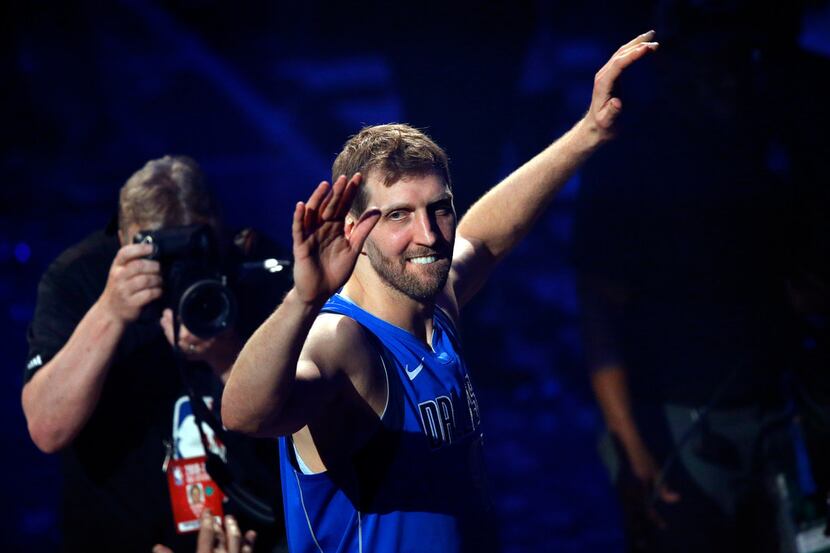 Dallas Mavericks forward Dirk Nowitzki waves to fans as he leaves the court following a...