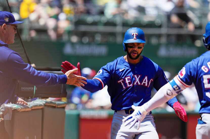 Texas Rangers' Leody Taveras, center, celebrates with manager Bruce Bochy, left, and Adolis...