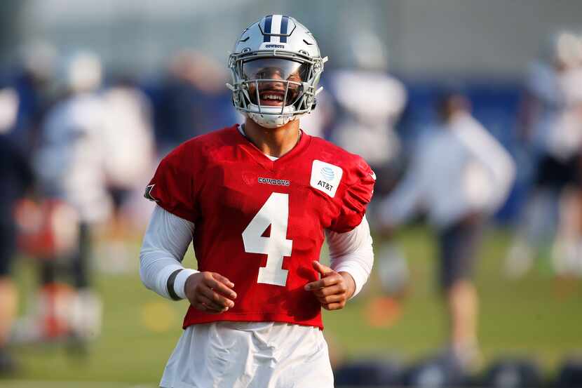 Dallas Cowboys quarterback Dak Prescott (4) laughs after completing a drill during training...