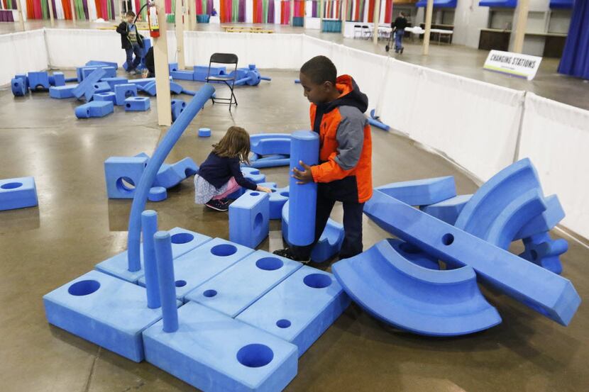 Ava Meyers, 5, left, and Noah Cypull, 8, play in the Imagination Playground at Fair Park on...