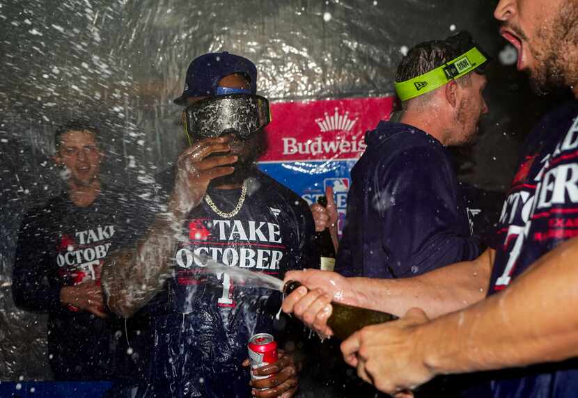 Texas Rangers right fielder Adolis García, wearing chain, celebrates clinching a playoff...