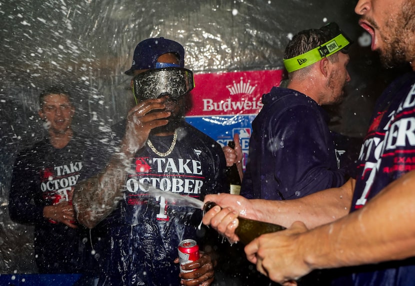 Texas Rangers right fielder Adolis García, wearing chain, celebrates clinching a playoff...